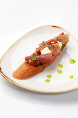 Bruschetta with prosciutto, mozzarella, sun-dried tomatoes and guacamole