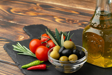 Olive oil, olives and tomatoes on wooden background