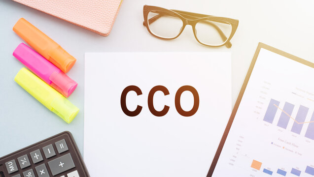 CCO Chief Commercial officer. Text on notepad and office accessories on white desk