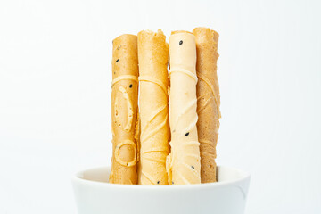 Thai crispy dessert roll isolated on white background. Close up of Tong Muan or Thai wafer in white cup.