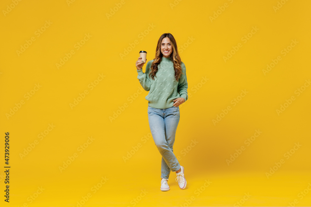 Sticker Full body young smiling woman 30s in green knitted sweater hold takeaway delivery craft paper brown cup coffee to go isolated on plain yellow color background studio portrait People lifestyle concept