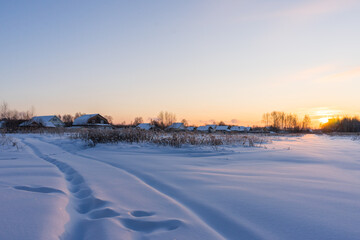 Village on a sunny morning and snowy field