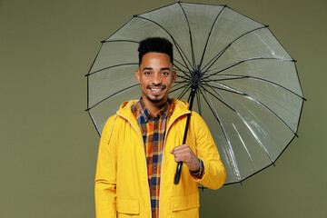 Happy smiling young black man 20s years old wears yellow raintcoat shirt hold umbrella look camera...