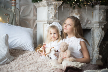 Little girls play in the bedroom in the morning before Christmas. Winter holidays, Christmas, New Year.