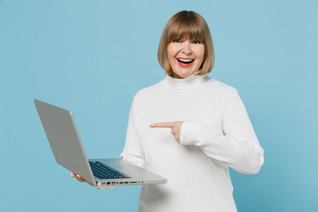 Elderly smiling copywriter grandmother woman 50s in white knitted sweater hold use work point on...