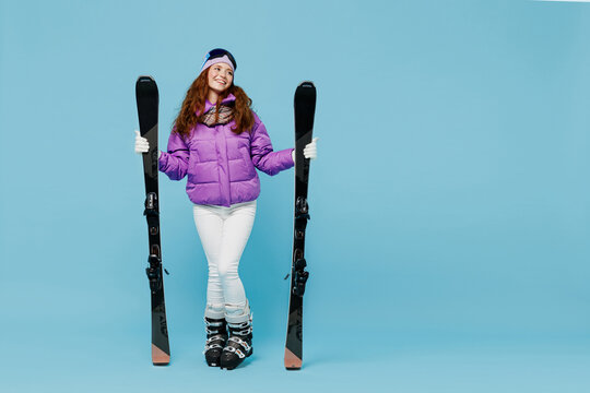 Full size skier happy fun woman in warm purple padded windbreaker jacket goggles mask spend extreme weekend in mountains hld ski look aside on workspace area isolated on plain blue background studio