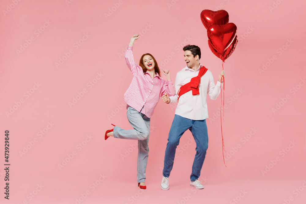 Poster Full size young couple two friend woman man in shirt hold bunch of red inflatable balloon dance isolated on plain pastel pink background studio portrait Valentine's Day birthday holiday party concept