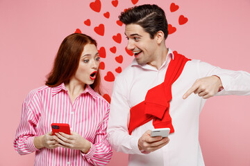 Young couple two friends woman man 20s in casual shirt using point finger on mobile cell phone isolated on plain pastel pink background studio portrait. Valentine's Day birthday holiday party concept