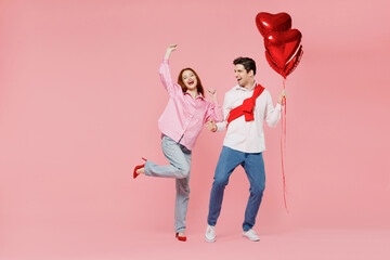 Full size young couple two friend woman man in shirt hold bunch of red inflatable balloon dance isolated on plain pastel pink background studio portrait Valentine's Day birthday holiday party concept