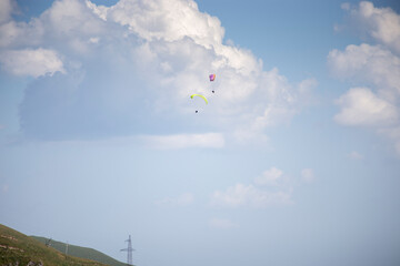 Paragliding with a pair of instructors. Bright blue sky with beautiful white fluffy clouds. Leisure with active adventures.