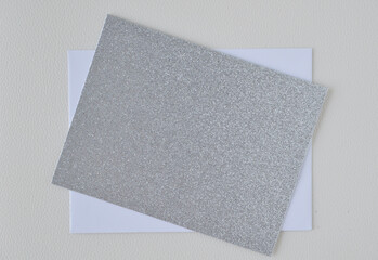 Silver glitter festive season card on top of a white envelop