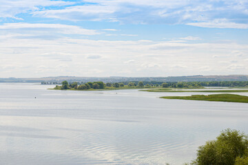 Summer landscape with a view of a wide river and a settlement on the far bank