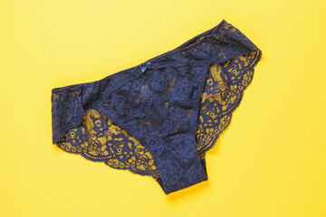 Dark blue women's panties on a yellow background, top view