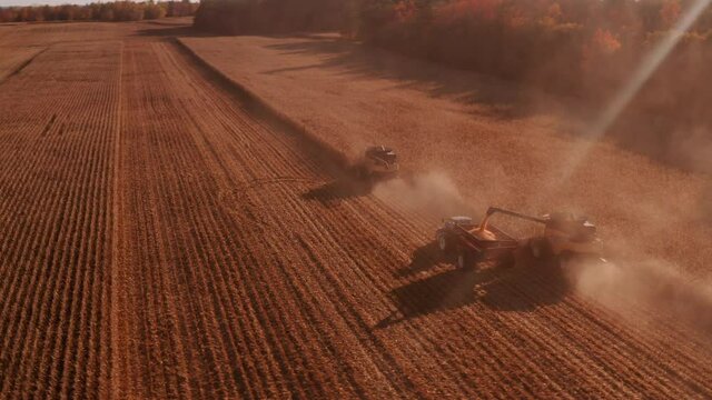 4K AERIAL FOOTAGE OF COMBINE OPERATION WITH SUPPORTING TRACTORS REAPING WEATH IN QUEBEC CANADA