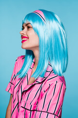 cheerful woman in blue wig posing fashion blue background