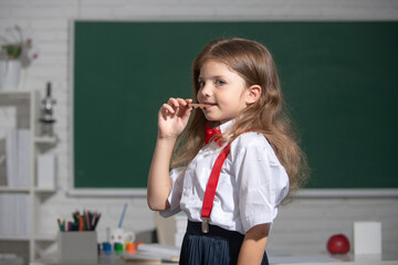 Portrait of cute, lovely, girl in school uniform eating chocolate in classroom. Elementary school...