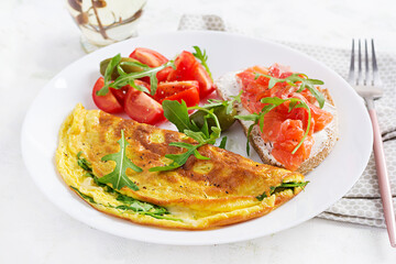 Breakfast. Omelette with cheese, green arugula and sandwich with salmon on white plate.  Frittata - italian omelet.