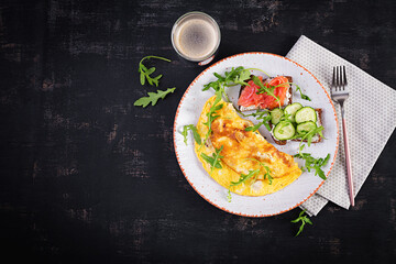 Breakfast. Omelette with cheese and sandwiches with salmon and cucumber on white plate. Frittata - italian omelet. Top view