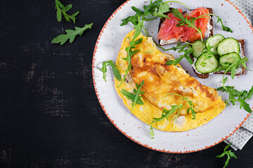 Breakfast. Omelette with cheese and sandwiches with salmon and cucumber on white plate. Frittata - italian omelet. Top view
