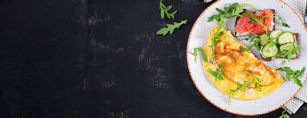 Breakfast. Omelette with cheese and sandwiches with salmon and cucumber on white plate. Frittata - italian omelet. Top view, banner