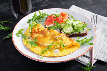 Breakfast. Omelette with cheese and sandwiches with salmon and cucumber on white plate. Frittata - italian omelet.