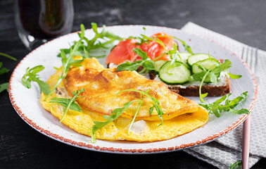 Breakfast. Omelette with cheese and sandwiches with salmon and cucumber on white plate. Frittata - italian omelet.
