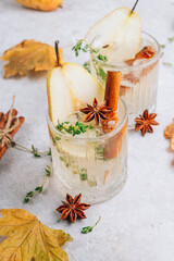 Traditional autumn spicy cocktail with pear. Cold pear white tea or mulled wine with cinnamon, thyme and anise on the light beige background