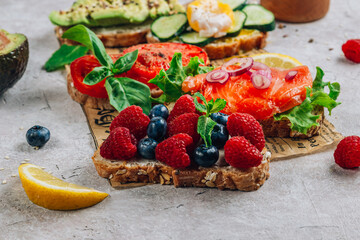 Breakfast Toast Variation with avocado, salmon, egg, cucumber, berries on baking paper