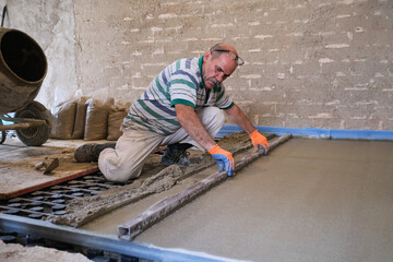Construction worker smoothing concrete above the radiant floor system.