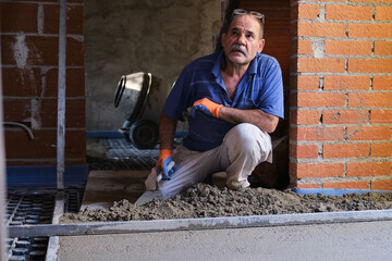 Builder listening to his boss while spreading concrete above the radiant floor.