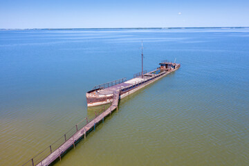 A half-sunken rusty barge at the last berth on the Ob River in Siberia, Russia, in summer