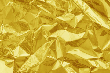 Shiny gold foil texture background, pattern of yellow wrapping paper with crumpled and wavy.