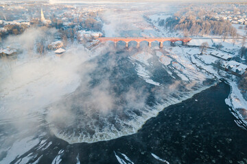 Venta Rapid waterfall, the widest waterfall in Europe and long brick bridge in foggy winter day, Kuldiga, Latvia. Captured from above