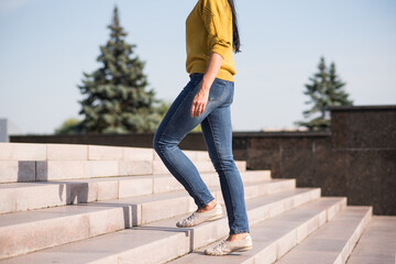 A young, beautiful and attractive Caucasian brunette girl in a yellow sweater climbing up the...