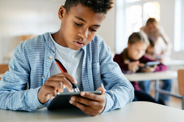 African American elementary student uses touchpad in classroom at school.