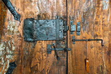 Close-up of old iron lock and hinges on heavy door made of barn wood