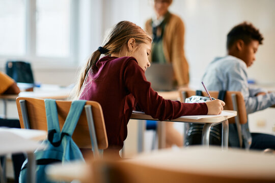 Rear view of schoolgirl writes exam during class in the classroom.