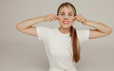 A young woman with a bandage on her nose after rhinoplasty rejoices