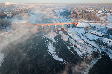 Venta Rapid waterfall, the widest waterfall in Europe and long brick bridge in foggy winter day,...