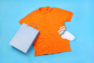 Blank t-shirt, bag and socks on blue background