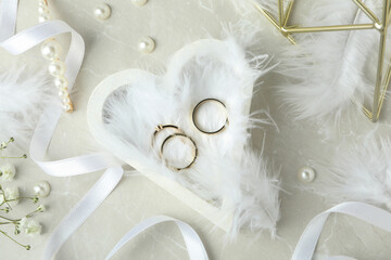 Concept of wedding accessories with wedding rings on white textured background