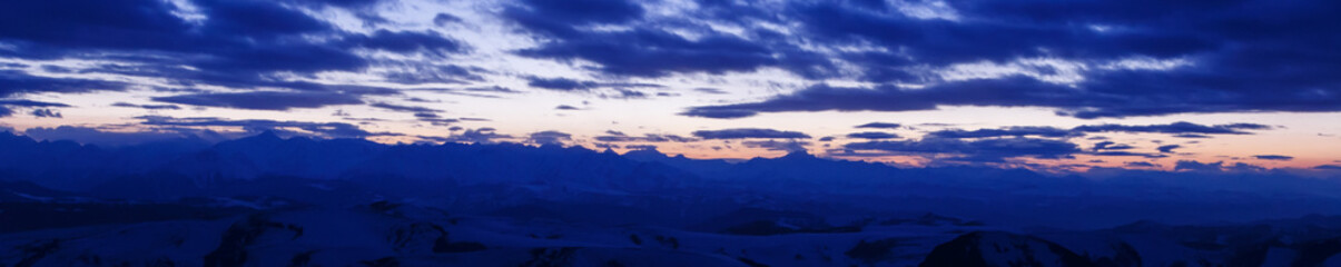 Elbrus in the clouds in the light of the sunset rays