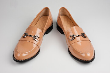 Beige patent leather leatherette shoes with buckle. Close-up shot.