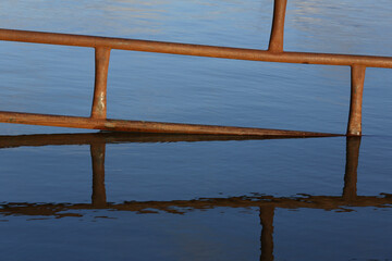 Close-up of a partially submerged fence in a flooded meadow
