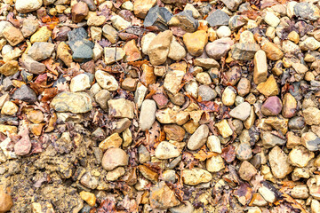 A pile of rough stones mixed with fallen autumn leaves at a construction site