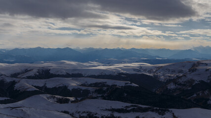 Fototapeta premium The setting sun illuminates the mountain range through the clouds