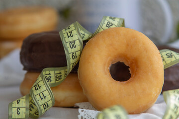 donuts or industrial pastries and measuring tape, diet and food concept