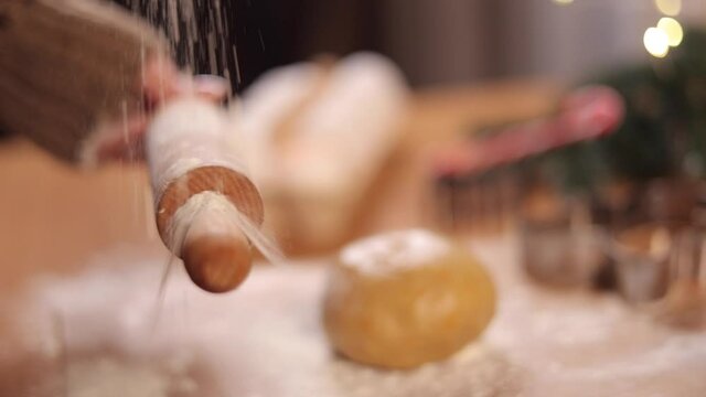 Woman sprinkles flour on rolling pin for making gingerbread. Christmas mood. Side view. Slow motion
