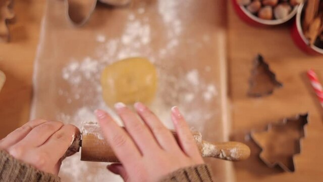 First person view of woman sprinkles flour on rolling pin for making gingerbread. Top view. Raw dough. Christmas mood