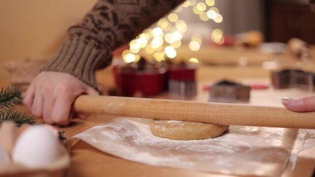 Woman using rolling pin for making gingerbread. Close-up of rolling raw dough for gingerbread. Christmas mood. Preparing for hollidays